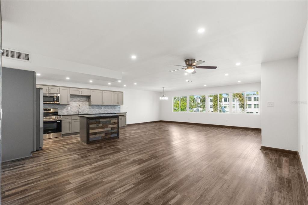 An open-concept kitchen and living area with gray cabinets, a kitchen island, and wood flooring — 225 COUNTRY CLUB DRIVE UNIT B221, LARGO, FL