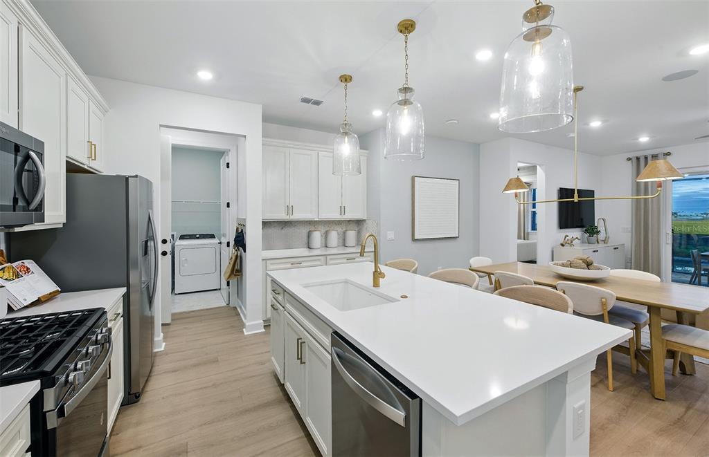 A modern kitchen features white cabinetry, a large quartz island, stainless steel appliances, and pendant lighting — 320 FISHTAIL PLACE, PALM COAST, FL
