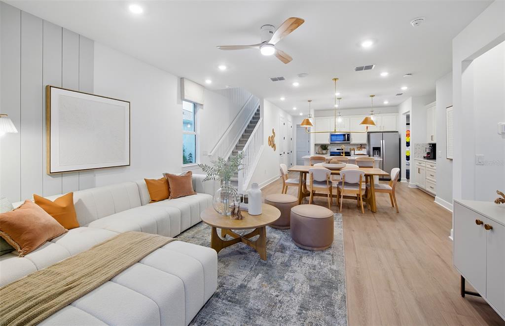 An open-concept living and dining area features a white sectional, wood flooring, and modern lighting — 320 FISHTAIL PLACE, PALM COAST, FL