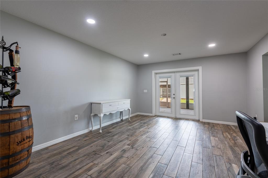 A room with gray walls, wood-look tile flooring, a wine barrel rack, and French doors — 16142 BREAKWATER LANE, SPRING HILL, FL