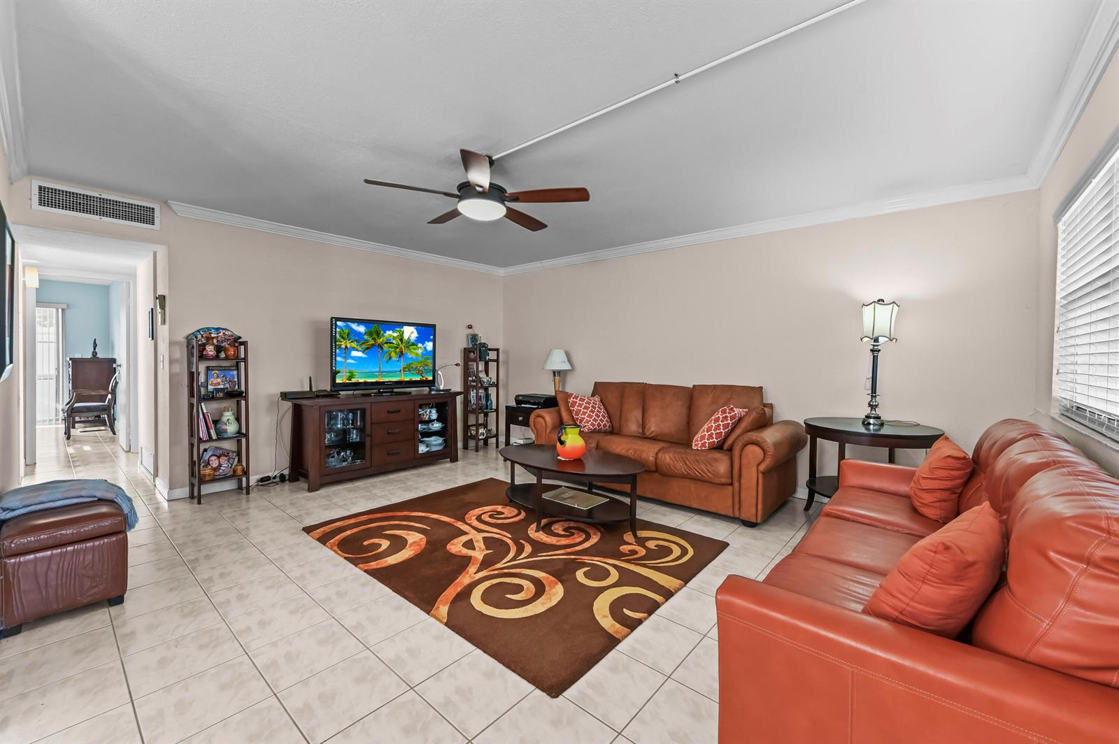 A living room features tile floors, two leather sofas, a television console, and a ceiling fan — 213 Brittany, Delray Beach FL 33446, DELRAY BEACH, FL