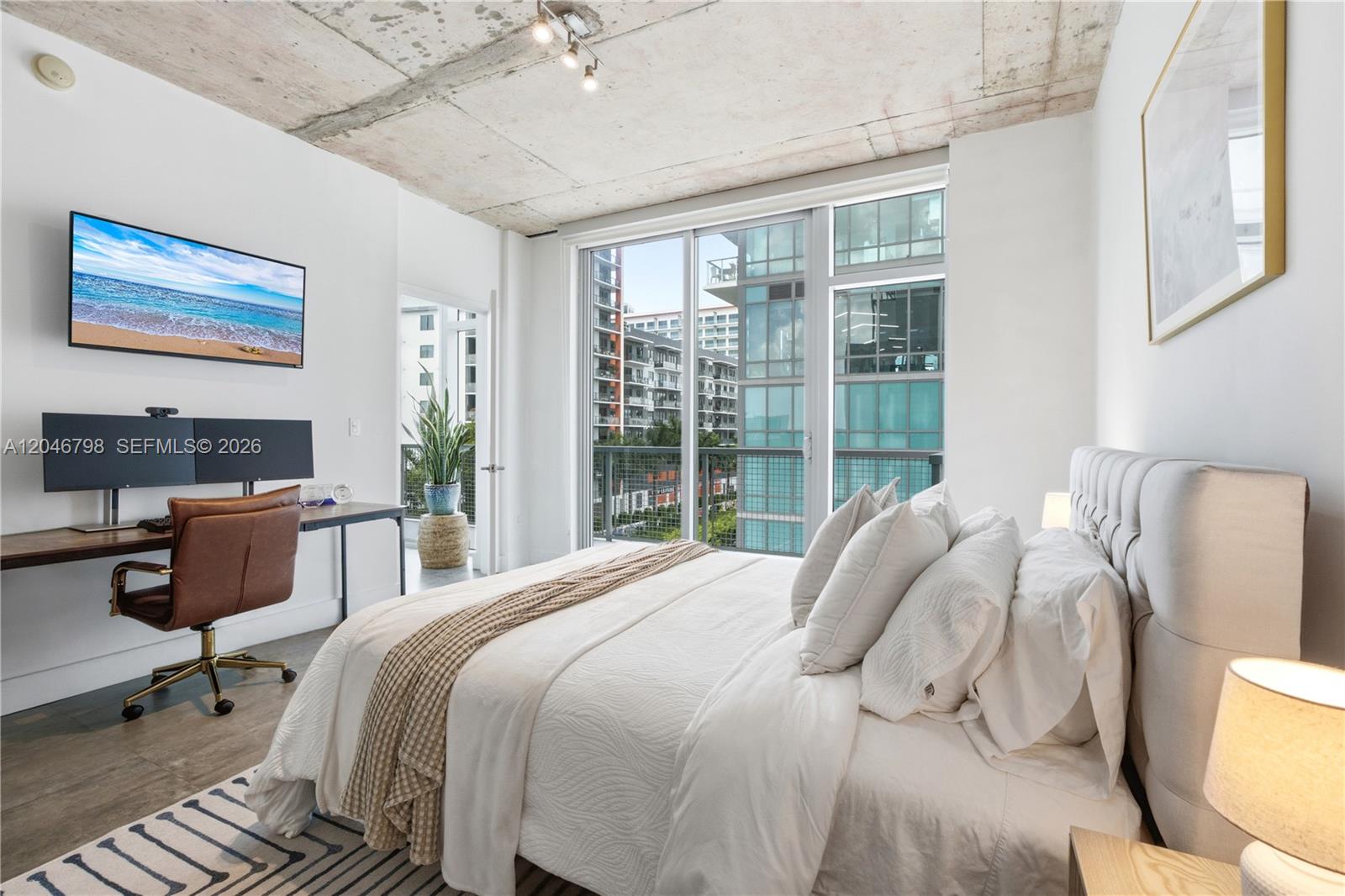 A bedroom features a bed, a desk, and a balcony with views of nearby buildings — 3301 NE 1st Ave, Miami FL 33137, MIAMI, FL