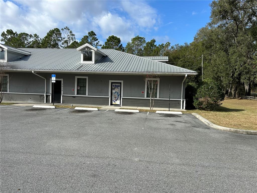 A gray commercial building with a metal roof and parking spaces in front — 3619 E CR 466, OXFORD, FL
