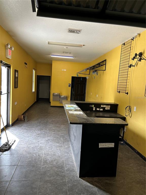A commercial space features yellow walls, a black service counter, and tiled flooring — 3619 E CR 466, OXFORD, FL