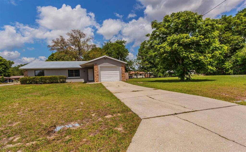 A single-story house with a gray roof, white garage door, and a concrete driveway — 7211 SE 120TH STREET, BELLEVIEW, FL