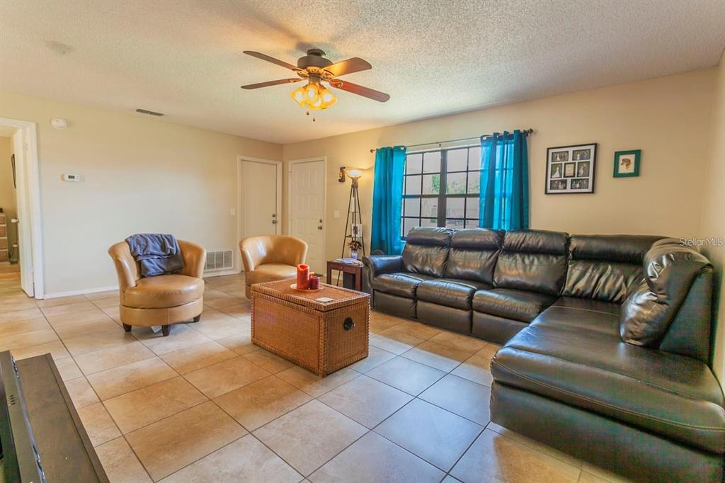 A living room features tile flooring, a leather sectional, two armchairs, and a ceiling fan — 7211 SE 120TH STREET, BELLEVIEW, FL