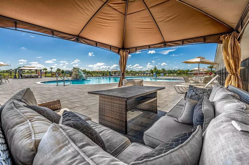 A covered patio with outdoor seating overlooks a swimming pool with a rock water feature — 0 HIGHWAY 630 E UNIT 409, LAKE WALES, FL