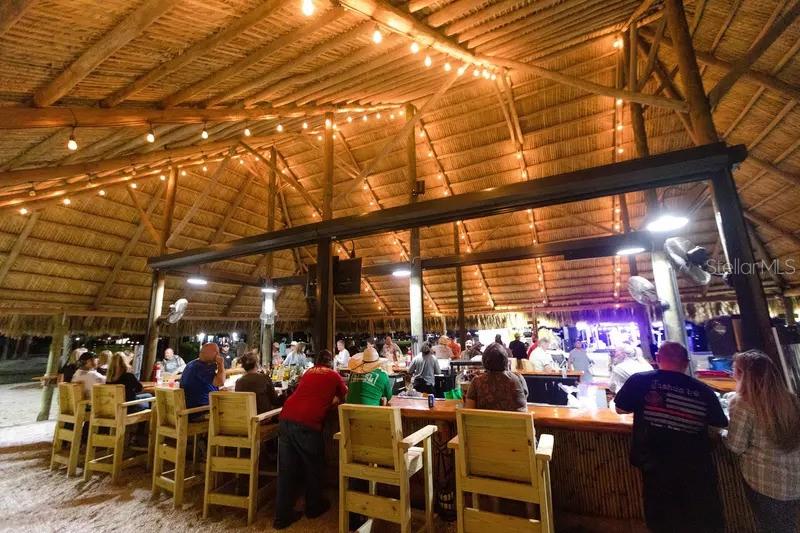 An open-air tiki bar features a thatched roof, string lights, and wooden bar stools — 0 HIGHWAY 630 E UNIT 409, LAKE WALES, FL