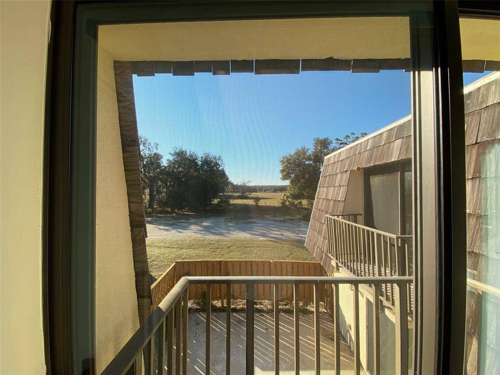 A view from a balcony looking out toward a grassy field and trees — 2911 PECAN AVENUE, LEESBURG, FL