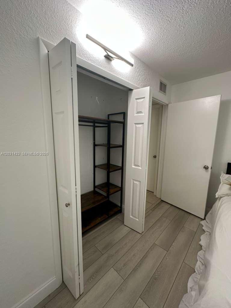 A bedroom closet with open shelving and a hanging rod sits beside a closed door — MIAMI, FL