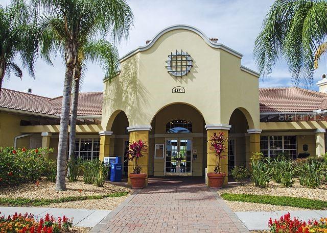 The exterior of a light yellow building features a central arched entryway and palm trees — 4862 CAYVIEW AVENUE UNIT 20909, ORLANDO, FL