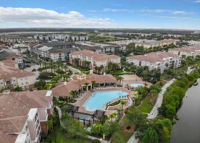 An aerial view shows a multi-story apartment complex with a central swimming pool and clubhouse — 4862 CAYVIEW AVENUE UNIT 20909, ORLANDO, FL