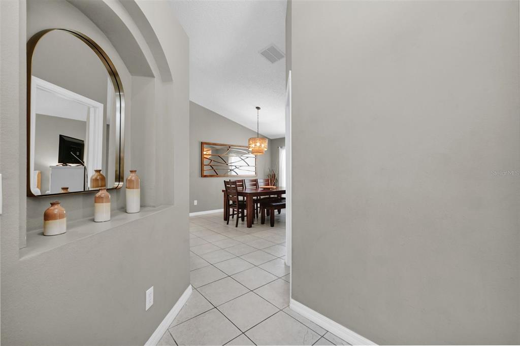 A view from a hallway looking into a dining room with tiled floors — 153 BAREFOOT BEACH WAY, KISSIMMEE, FL