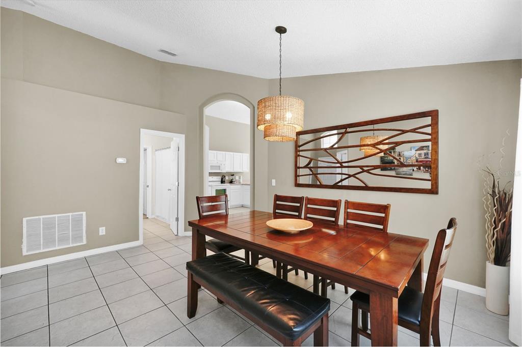 A dining room with a wooden table, chairs, a bench, and a decorative wall mirror — 153 BAREFOOT BEACH WAY, KISSIMMEE, FL