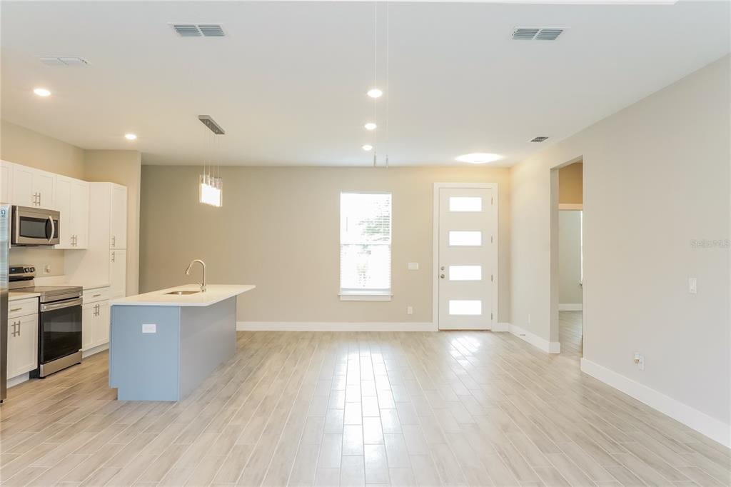 A kitchen with a light blue island and white cabinets opens to a living area — 202 SNAPPER WAY, KISSIMMEE, FL
