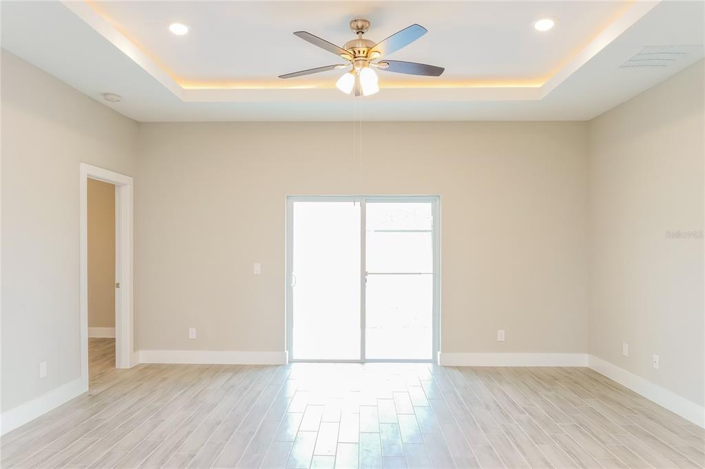 A bright, empty room features a tray ceiling with recessed lighting, a ceiling fan, and tile floors — 202 SNAPPER WAY, KISSIMMEE, FL