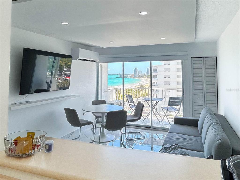 A living and dining area features a balcony with ocean views and tile flooring — 4837 AVE ISLA VERDE UNIT 607, CAROLINA, PR