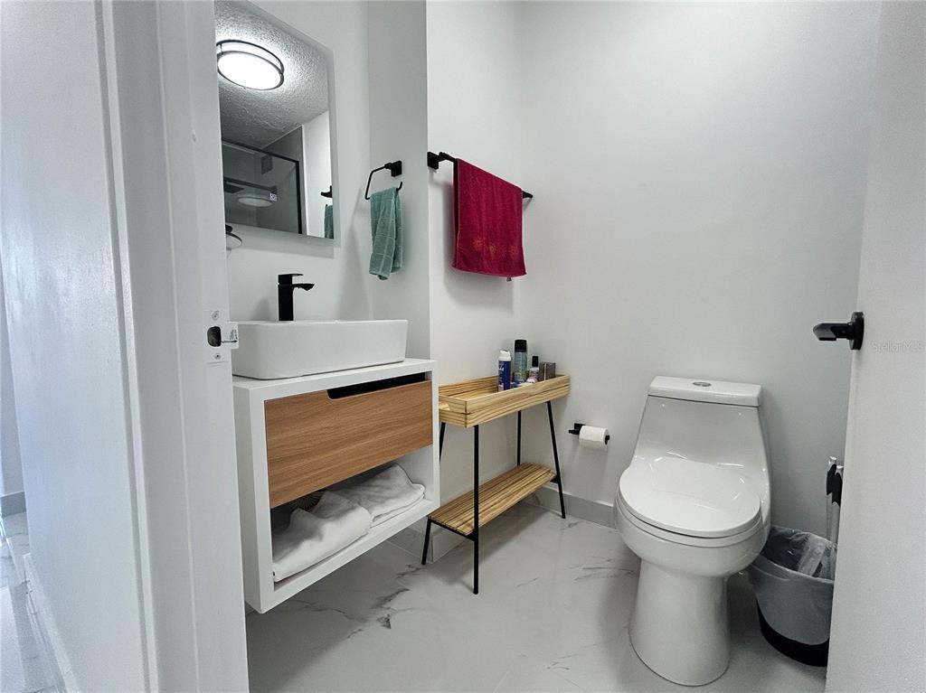 A modern bathroom features a floating wood vanity, vessel sink, and white toilet — 4837 AVE ISLA VERDE UNIT 607, CAROLINA, PR