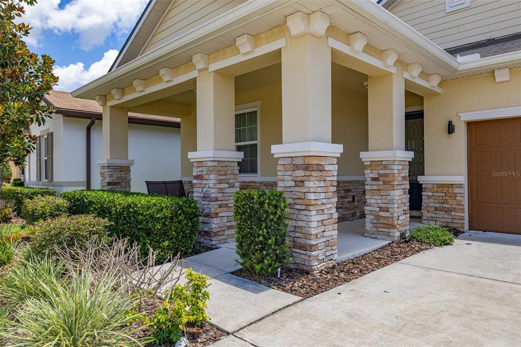 A covered front porch features stone-based columns and a concrete walkway leading to the entrance — 1222 YORKSHIRE COURT, DAVENPORT, FL