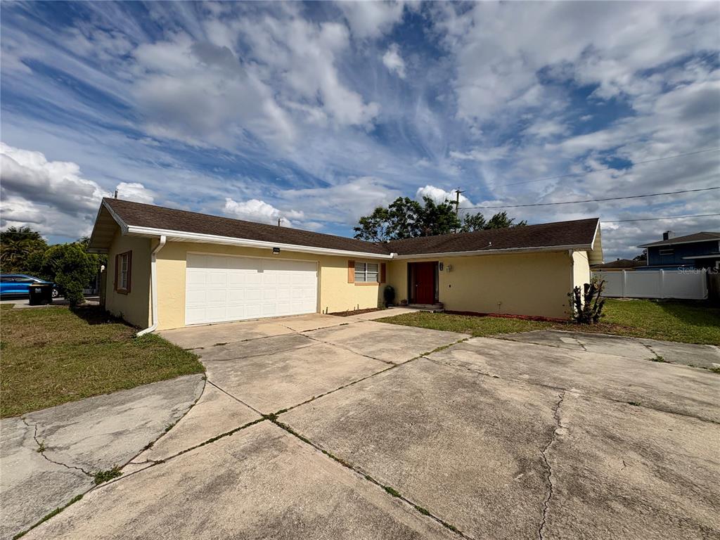A single-story house with a yellow exterior, a two-car garage, and a concrete driveway — 728 LAKE NED ROAD, WINTER HAVEN, FL