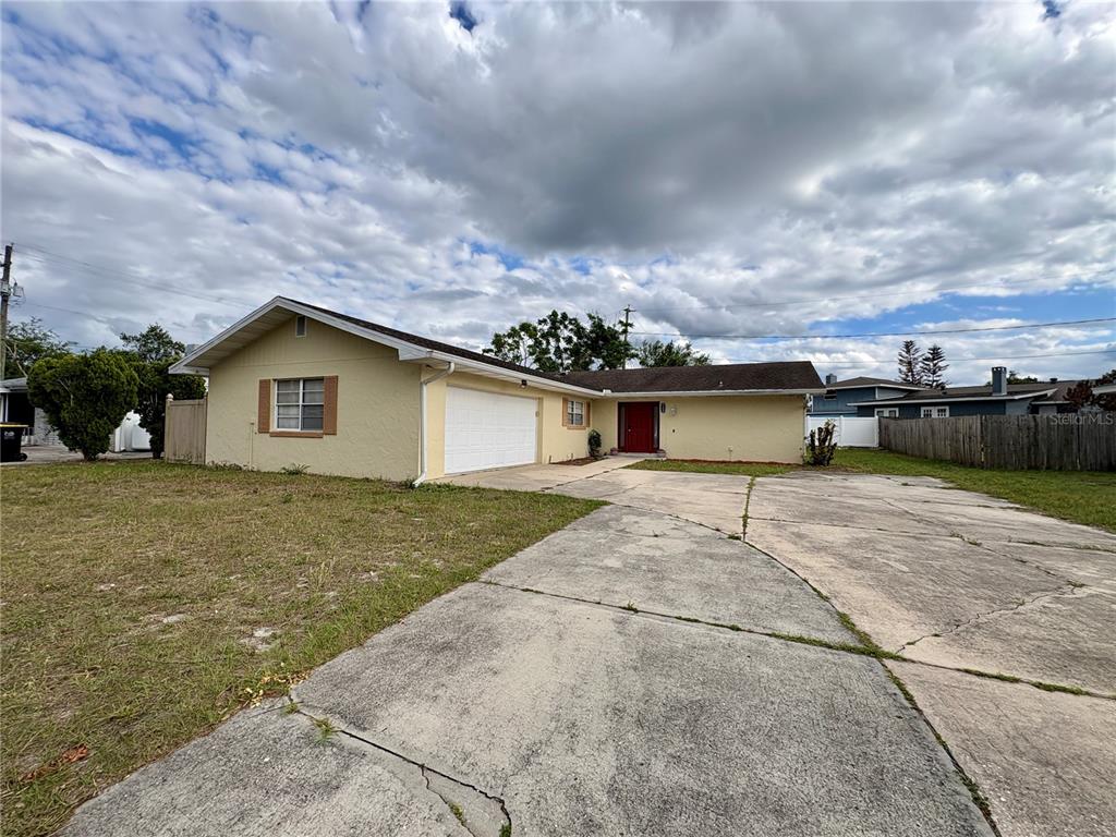 A single-story house with a yellow exterior, a two-car garage, and a large concrete driveway — 728 LAKE NED ROAD, WINTER HAVEN, FL