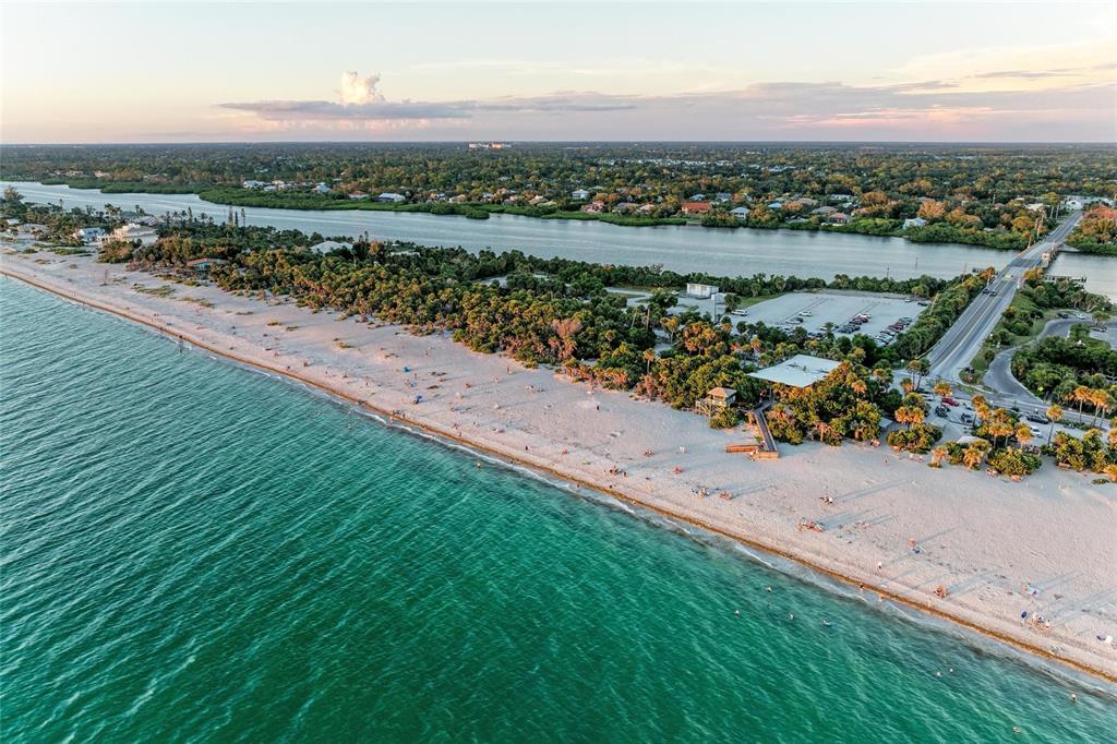 An aerial view shows a sandy beach, turquoise water, a parking lot, and a bridge — 7110 MANASOTA KEY ROAD, ENGLEWOOD, FL