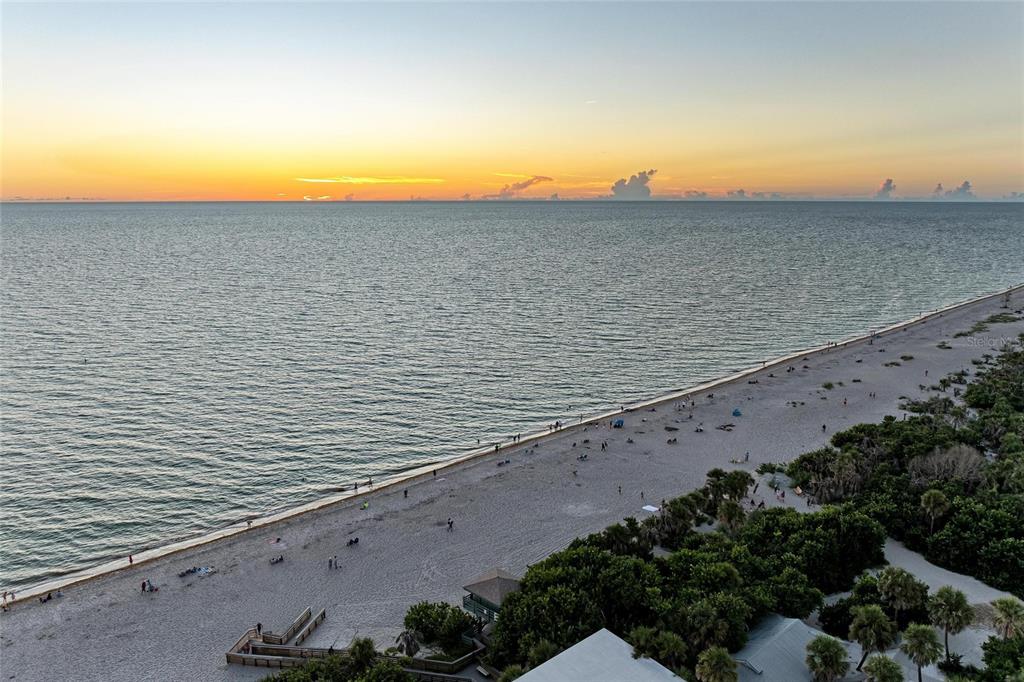 An aerial view shows a sandy beach along the ocean at sunset — 7110 MANASOTA KEY ROAD, ENGLEWOOD, FL