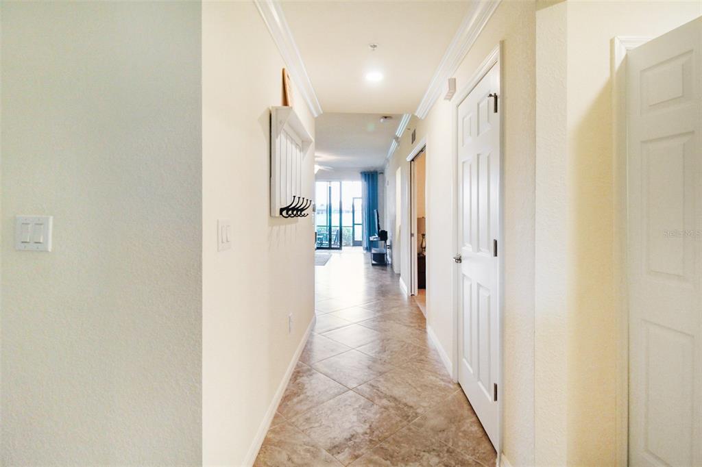 A tiled hallway leads toward a bright living area with a sliding glass door — 5517 PALMER CIRCLE UNIT 105, BRADENTON, FL
