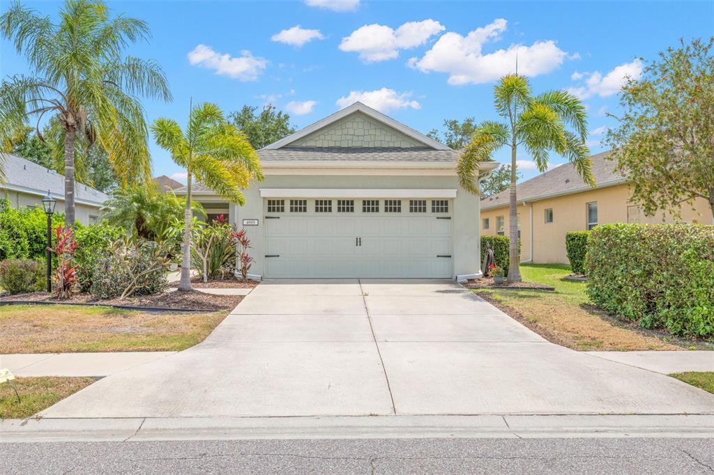 A single-story house with a light green exterior, a two-car garage, and two palm trees — 4919 BOSTON COMMON GLEN, BRADENTON, FL