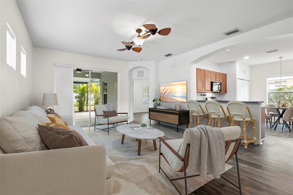 A bright living room features a sofa, armchairs, a coffee table, and an open kitchen — 4919 BOSTON COMMON GLEN, BRADENTON, FL