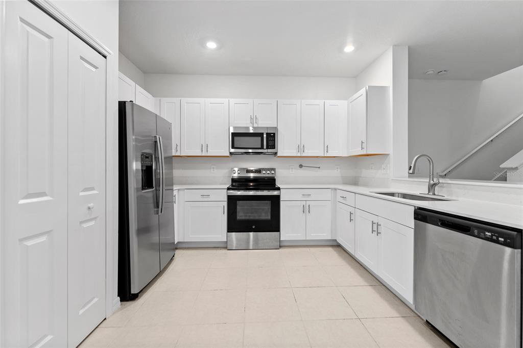 A kitchen with white cabinets, stainless steel appliances, and light-colored tile flooring — 5137 BENJAMIN ERIC STREET, ZEPHYRHILLS, FL