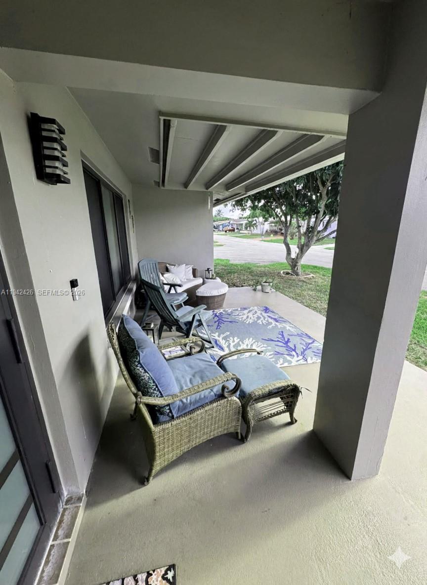 A covered patio features wicker furniture, a blue patterned rug, and a view of landscaping — 4701 NW 44th St, Tamarac FL 33319, TAMARAC, FL