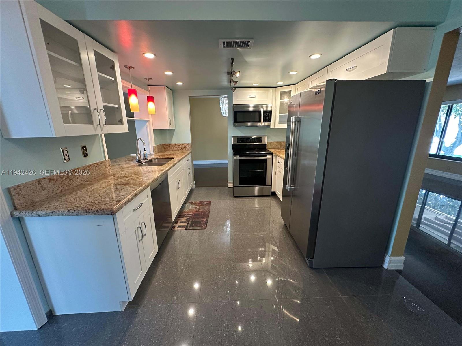 A kitchen features white cabinets, granite countertops, stainless steel appliances, and dark tile flooring — 4701 NW 44th St, Tamarac FL 33319, TAMARAC, FL