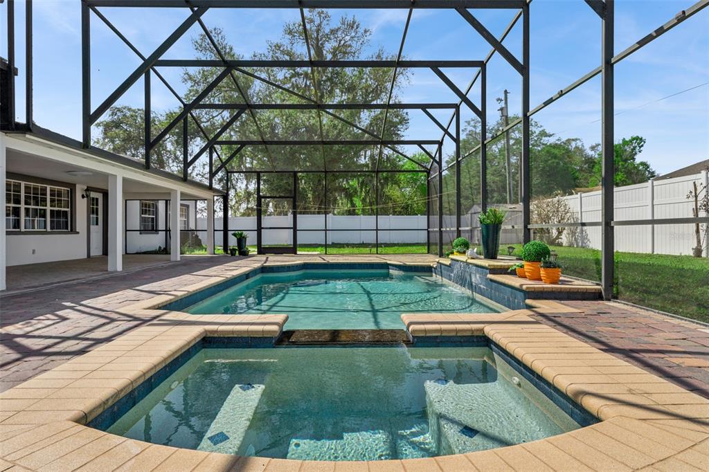 A screened-in patio features a swimming pool with an attached spa and brick pavers — 6053 NEW HOPE ROAD, ORLANDO, FL