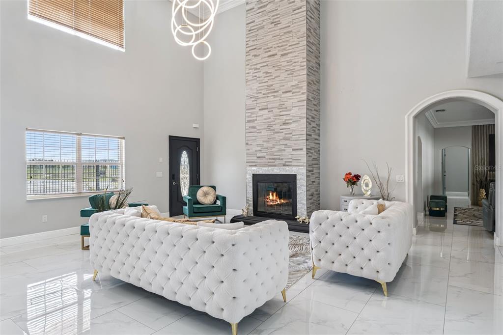 A bright living room features a tall stone fireplace, white tufted sofas, and tile flooring — 6053 NEW HOPE ROAD, ORLANDO, FL