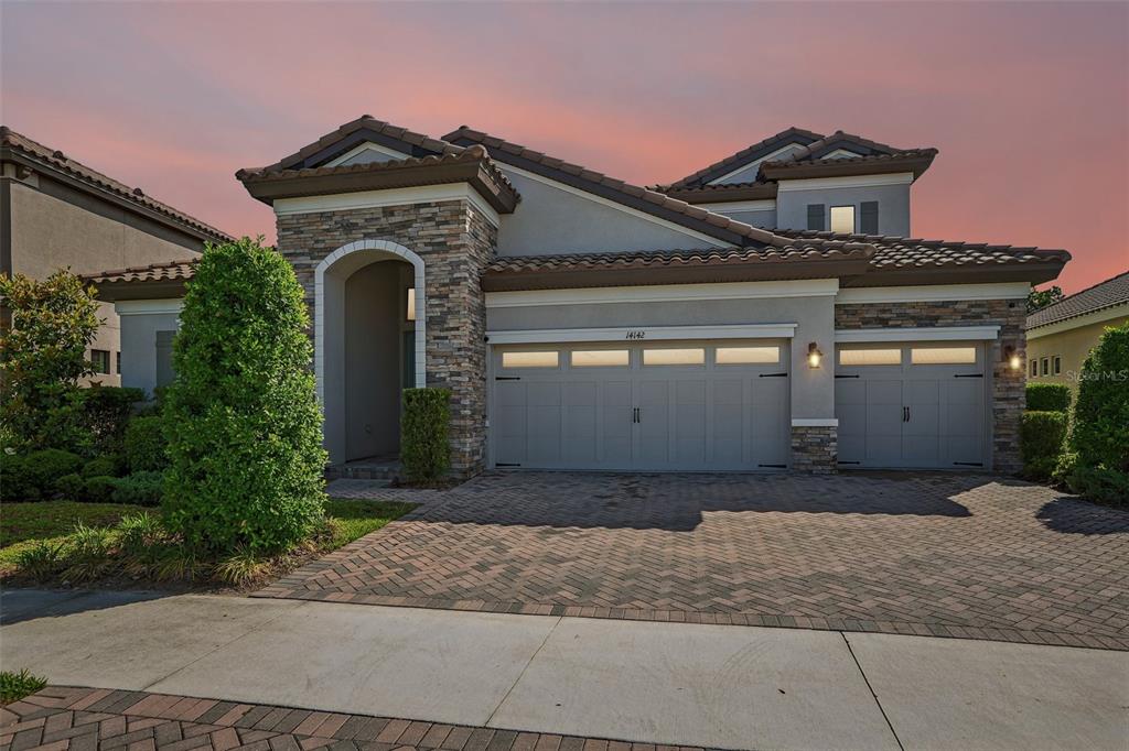 A two-story house with a stone-accented entryway, a three-car garage, and a paver driveway — 14142 SWISS BRIDGE DRIVE, RIVERVIEW, FL