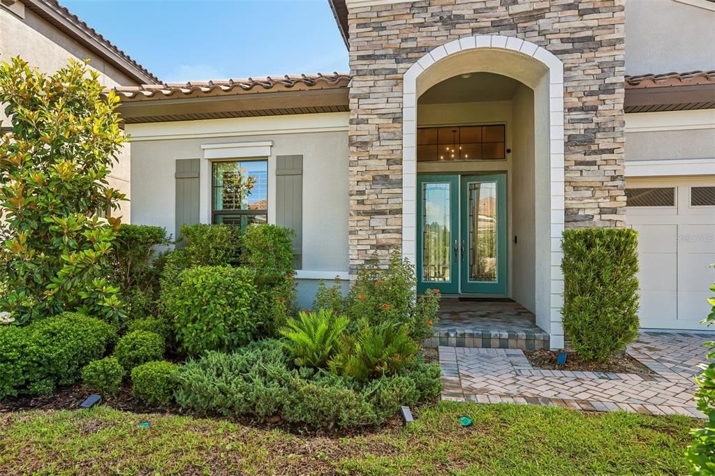 A stone-accented house exterior features a teal double front door and a brick walkway — 14142 SWISS BRIDGE DRIVE, RIVERVIEW, FL