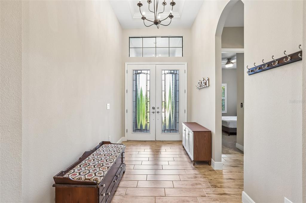 A bright entryway features a double front door, tile flooring, and a wooden storage bench — 14142 SWISS BRIDGE DRIVE, RIVERVIEW, FL