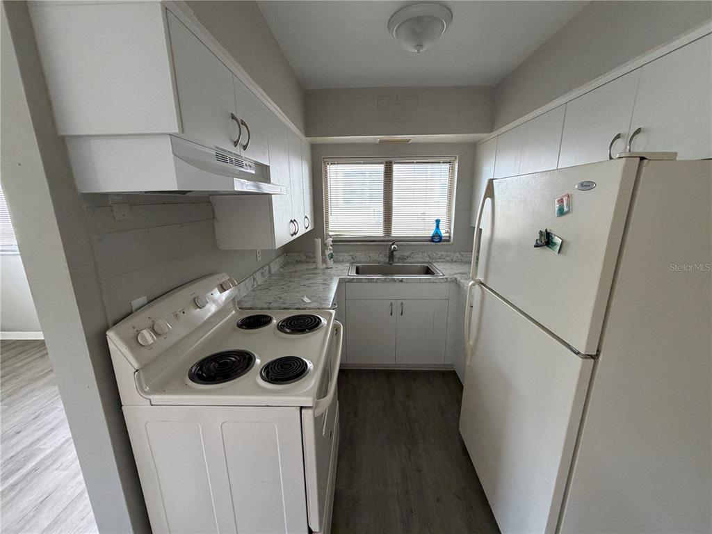 A galley-style kitchen features white cabinets, white appliances, and light-colored laminate countertops — 615 OAK AVENUE, CLEARWATER, FL