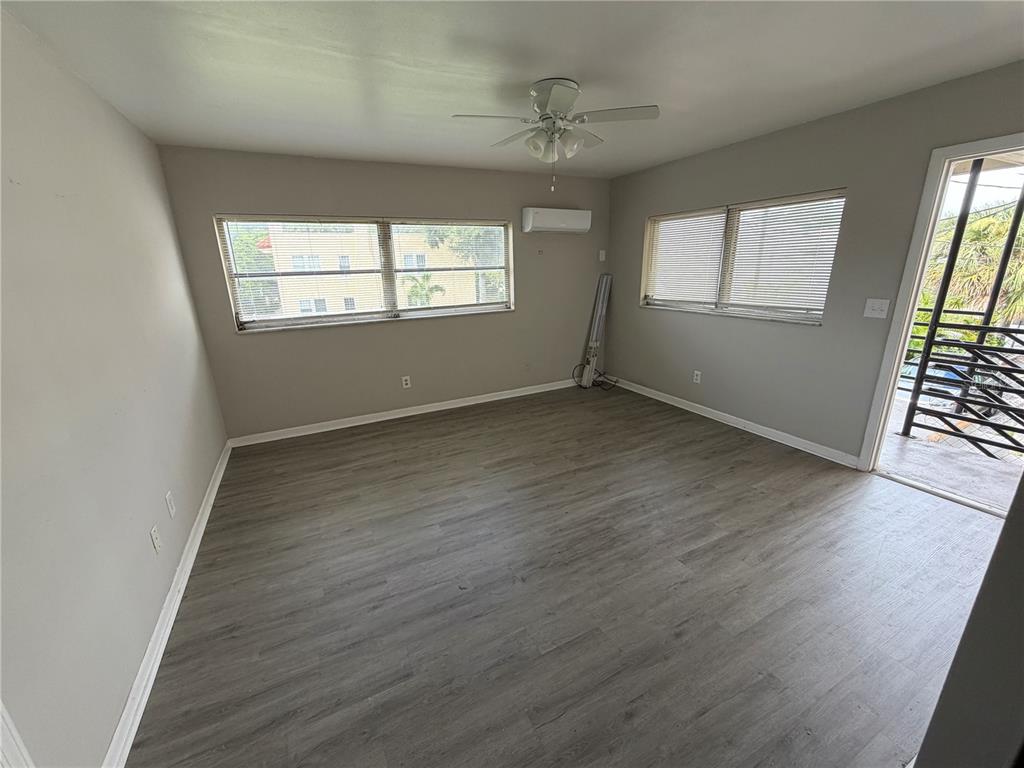 An empty room features gray wood-look flooring, light-colored walls, a ceiling fan, and window blinds — 615 OAK AVENUE, CLEARWATER, FL