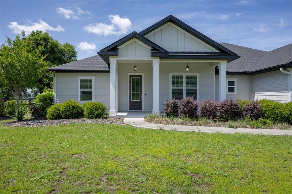 A light gray house with a dark roof and a covered front porch entrance — 1146 SW MANDIBA DRIVE, LAKE CITY, FL