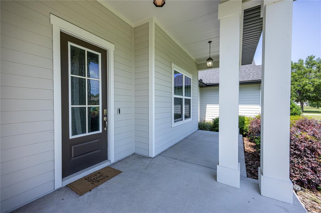 A covered front porch features a dark brown door, light siding, and white support columns — 1146 SW MANDIBA DRIVE, LAKE CITY, FL
