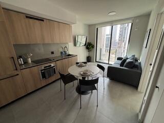 A modern studio apartment featuring a kitchen with wood cabinets, a dining table, and sofa — 121 NE 5th Street, Miami FL 33132, MIAMI, FL