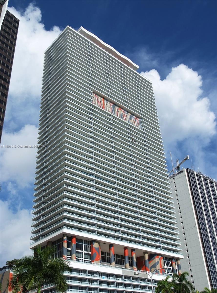 A tall, modern residential skyscraper features a white facade with numerous balconies and colorful columns — 50 Biscayne Blvd # 5211, Miami FL 33132, MIAMI, FL
