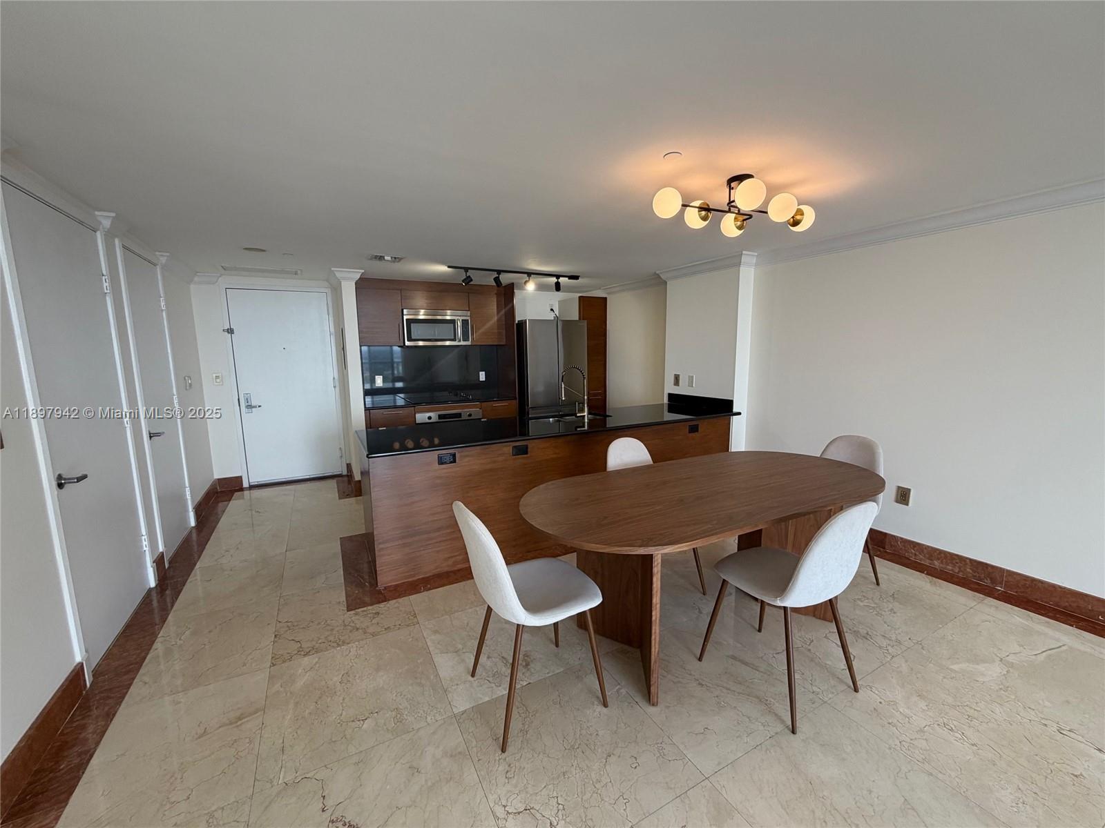 A dining area with an oval table and chairs sits before an open kitchen — 50 Biscayne Blvd # 5211, Miami FL 33132, MIAMI, FL