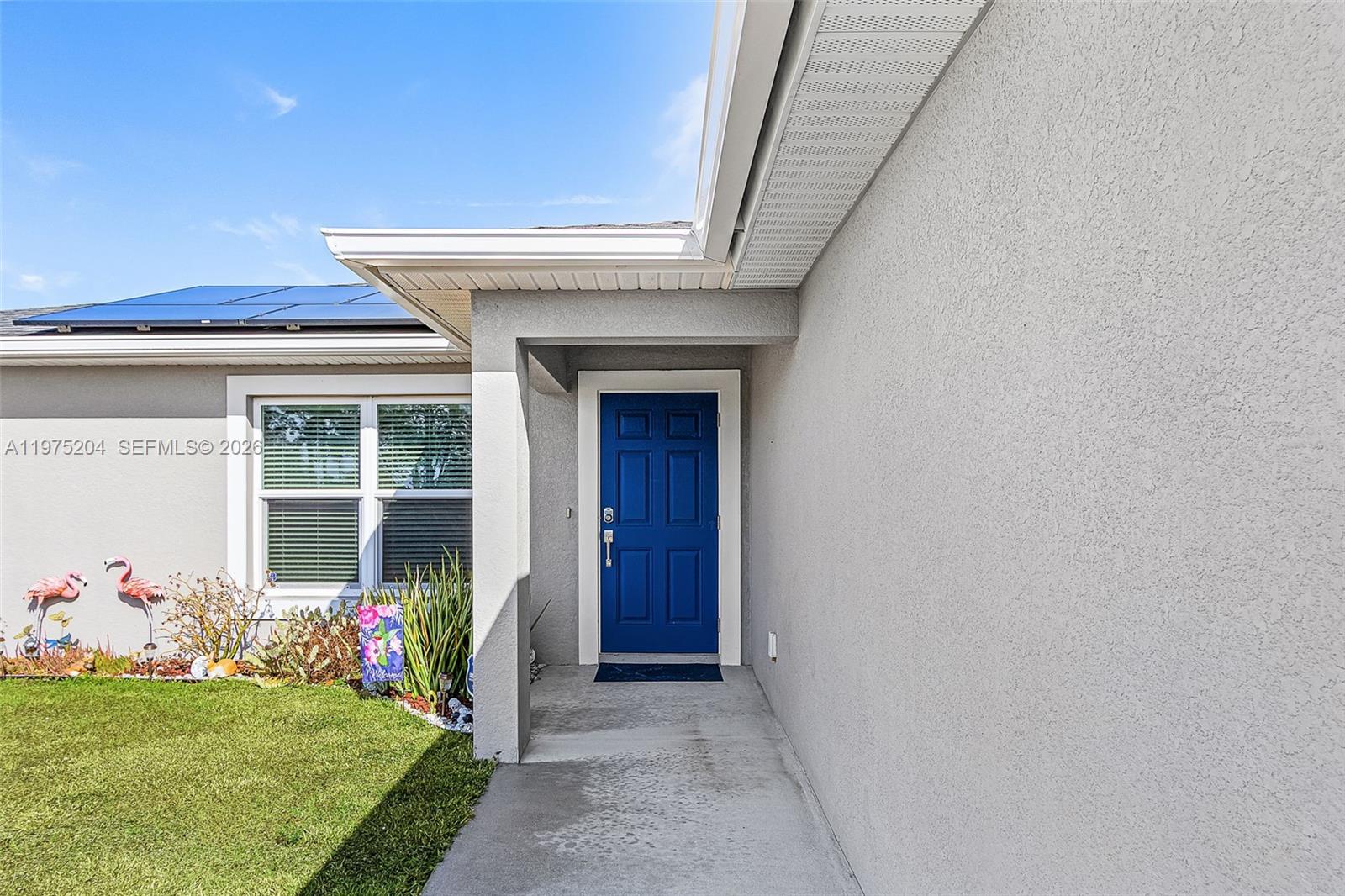 A single-story house with a gray stucco exterior, a two-car garage, and rooftop solar panels — 9032 Meadow Circle, La Belle FL 33935, LA BELLE, FL