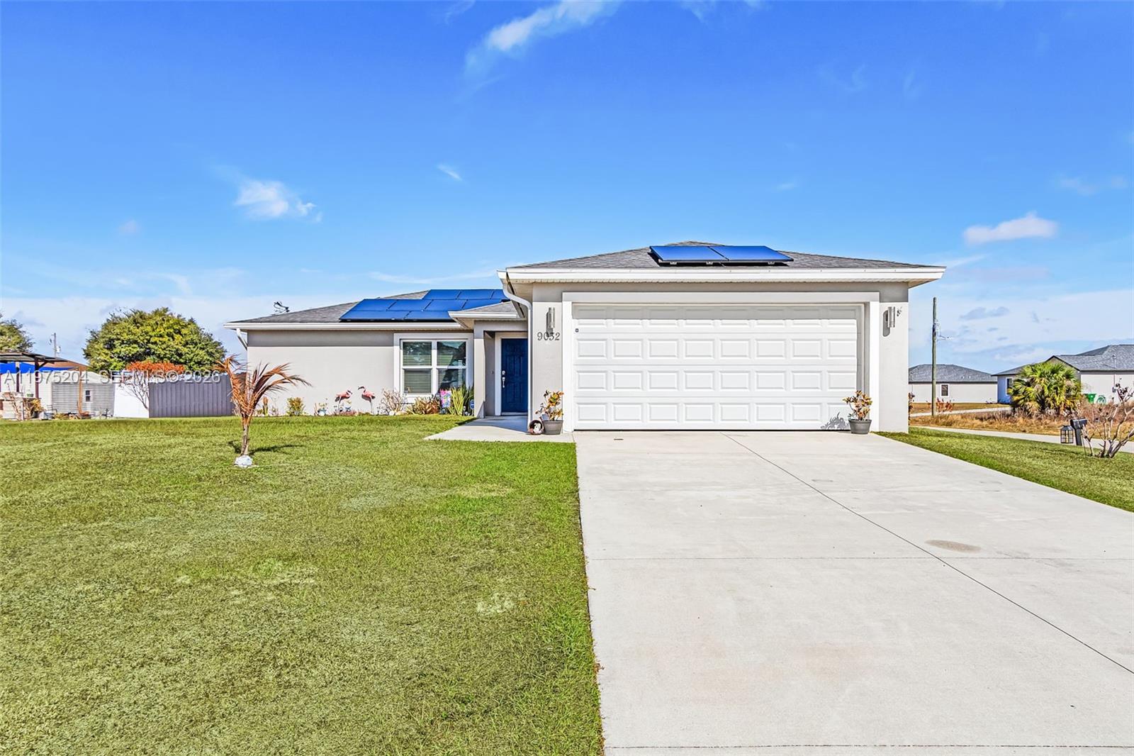 An aerial view shows a single-story house with solar panels on the roof and a driveway — 9032 Meadow Circle, La Belle FL 33935, LA BELLE, FL