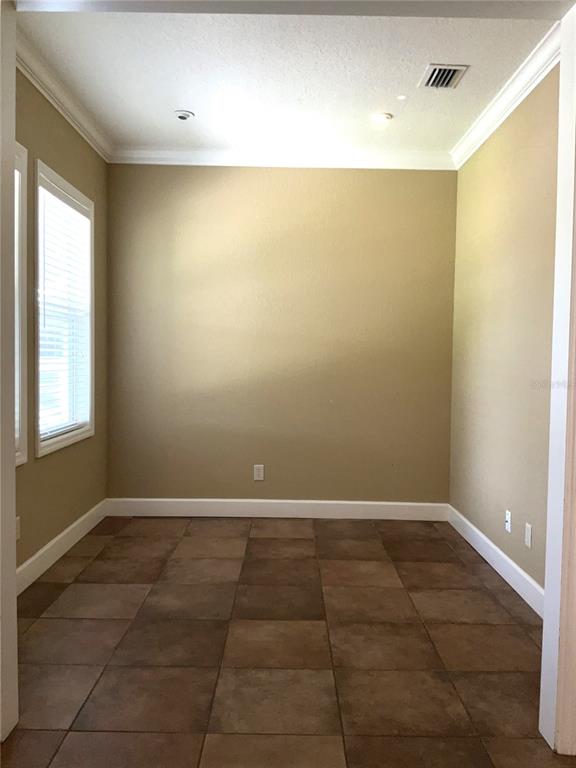 An empty room with tan walls, large brown floor tiles, and a window with blinds — 3613 S SUMMERLIN AVENUE, ORLANDO, FL