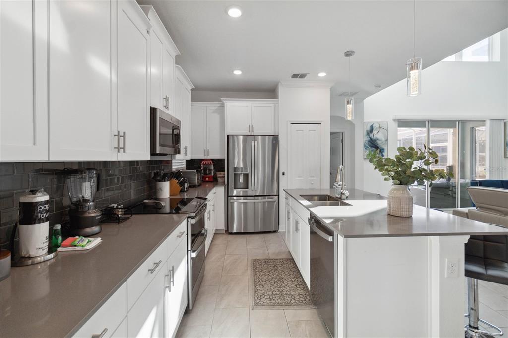 A modern kitchen features white cabinets, stainless steel appliances, a center island, and dark countertops — 1009 LEADER, DAVENPORT, FL