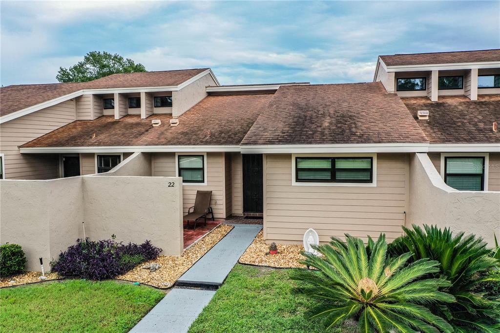 The exterior of a tan, multi-level townhouse features a brown shingled roof and a walkway — 5225 IMPERIAL LAKES BOULEVARD UNIT 22, MULBERRY, FL